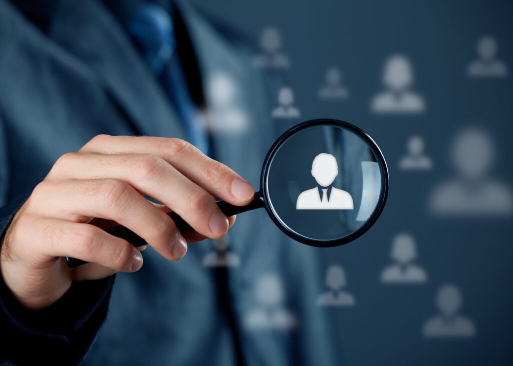 Hand holding magnifying glass with the logo of a man on its lens